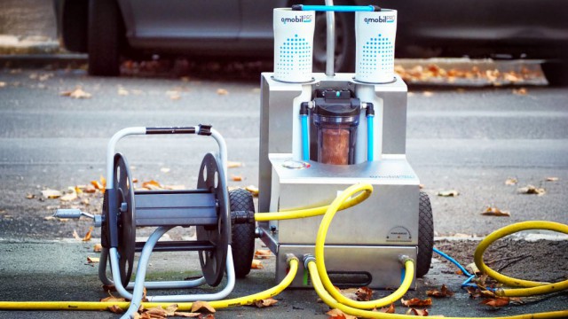 Ein mobiler Wasserfilter mit gelben Schläuchen und Filterpatronen bereitet vor Ort Reinigungswasser auf. Daneben steht eine Schlauchtrommel auf einem Gehweg mit Herbstlaub